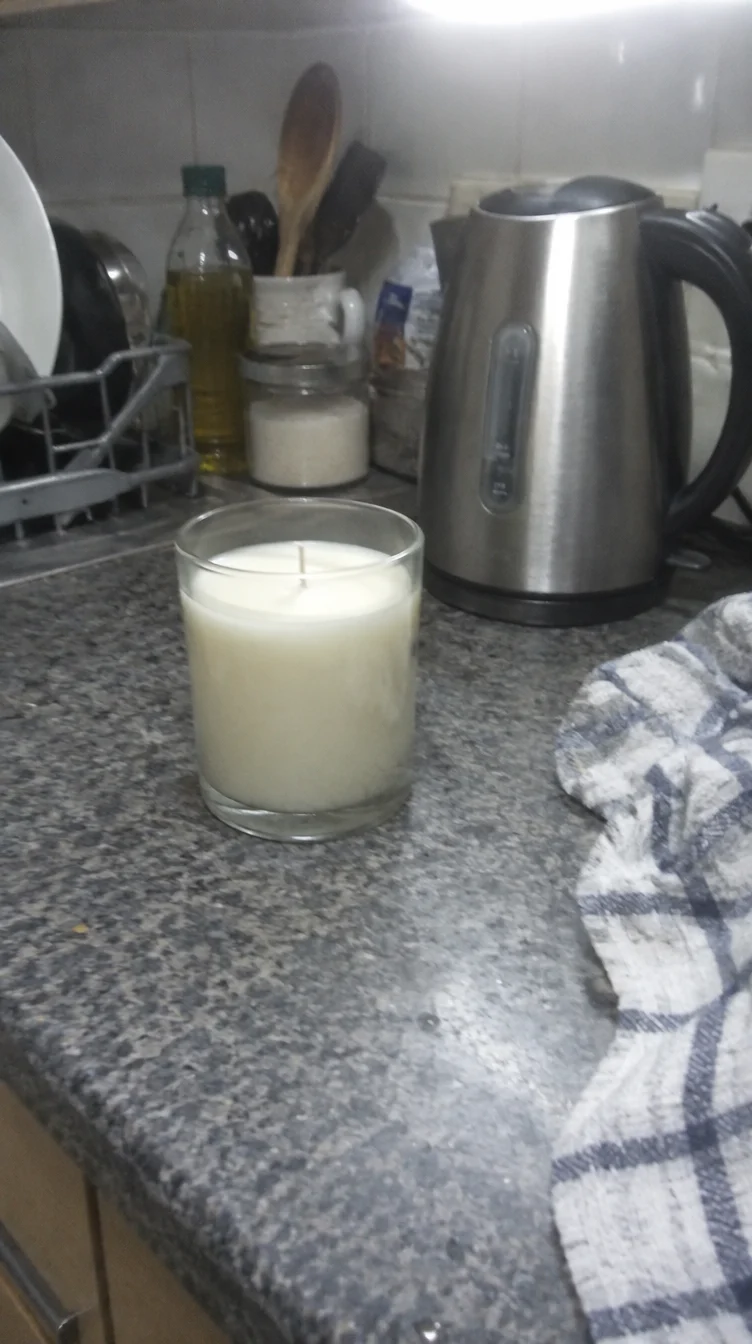 A rough phone photo of a candle on a kitchen counter.